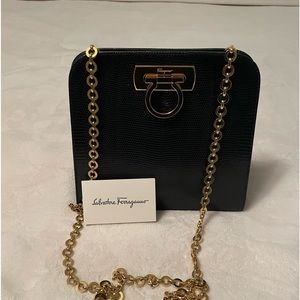 Authentic Salvatore Ferragamo black leather bag with shiny gold metal handle.